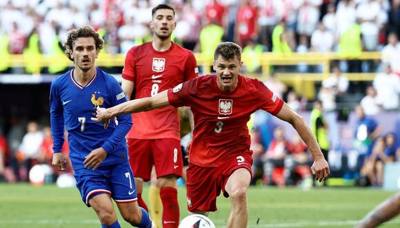 El centrocampista polaco #03 Pawel Dawidowicz (centro) lucha por el balón con el centrocampista francés #07 Antoine Griezmann (izq.) durante el partido de fútbol del Grupo D de la UEFA Euro 2024 entre Francia y Polonia en el BVB Stadion de Dortmund el 25 de junio de 2024. | Crédito: Kenzo Tribouillard / AFP