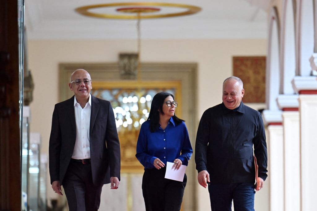 Venezuela's interim President Delcy Rodriguez (C), President of the National Assembly Jorge Rodriguez (L), and Minister of the Popular Power for Interior Diosdado Cabello walk in a hallway to arrive at a press conference at the Miraflores Presidential Palace in Caracas on January 14, 2026. Venezuela's interim president Delcy Rodriguez said on January 14, that her country was looking to "a new political era" after the January 3 ouster of leader Nicolas Maduro in a US military strike. (Photo by Juan BARRETO / AFP)