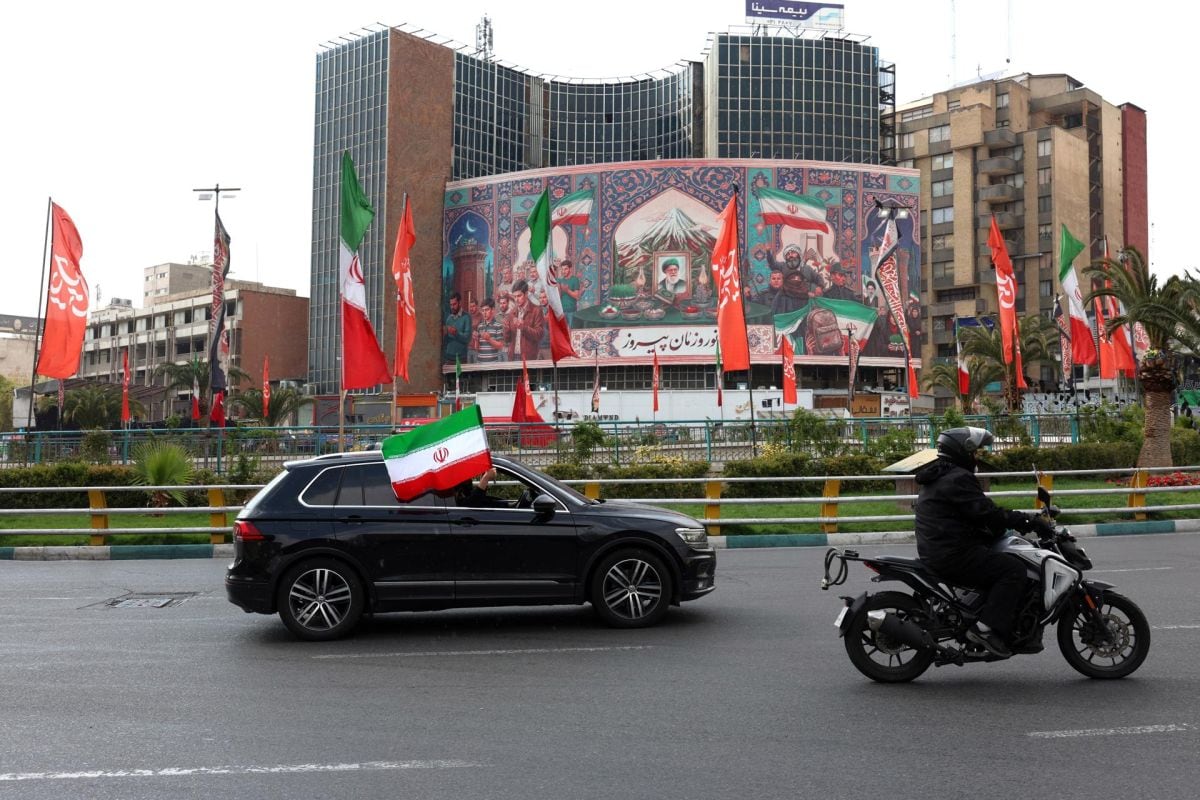 Un vehículo adornado con la bandera nacional iraní pasa junto a una pancarta política de gran tamaño en la plaza Valiasr de Teherán, Irán, el 31 de marzo de 2026. Foto: EFE/EPA/ABEDIN TAHERKENAREH