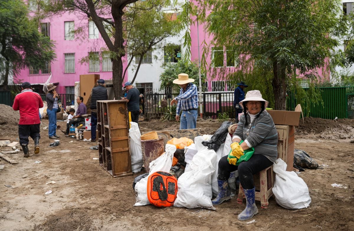 La gente se sienta en la calle con algunas pertenencias tras las fuertes lluvias en la ciudad de Arequipa, el 25 de febrero de 2026 (Foto: Diego Ramos / AFP)