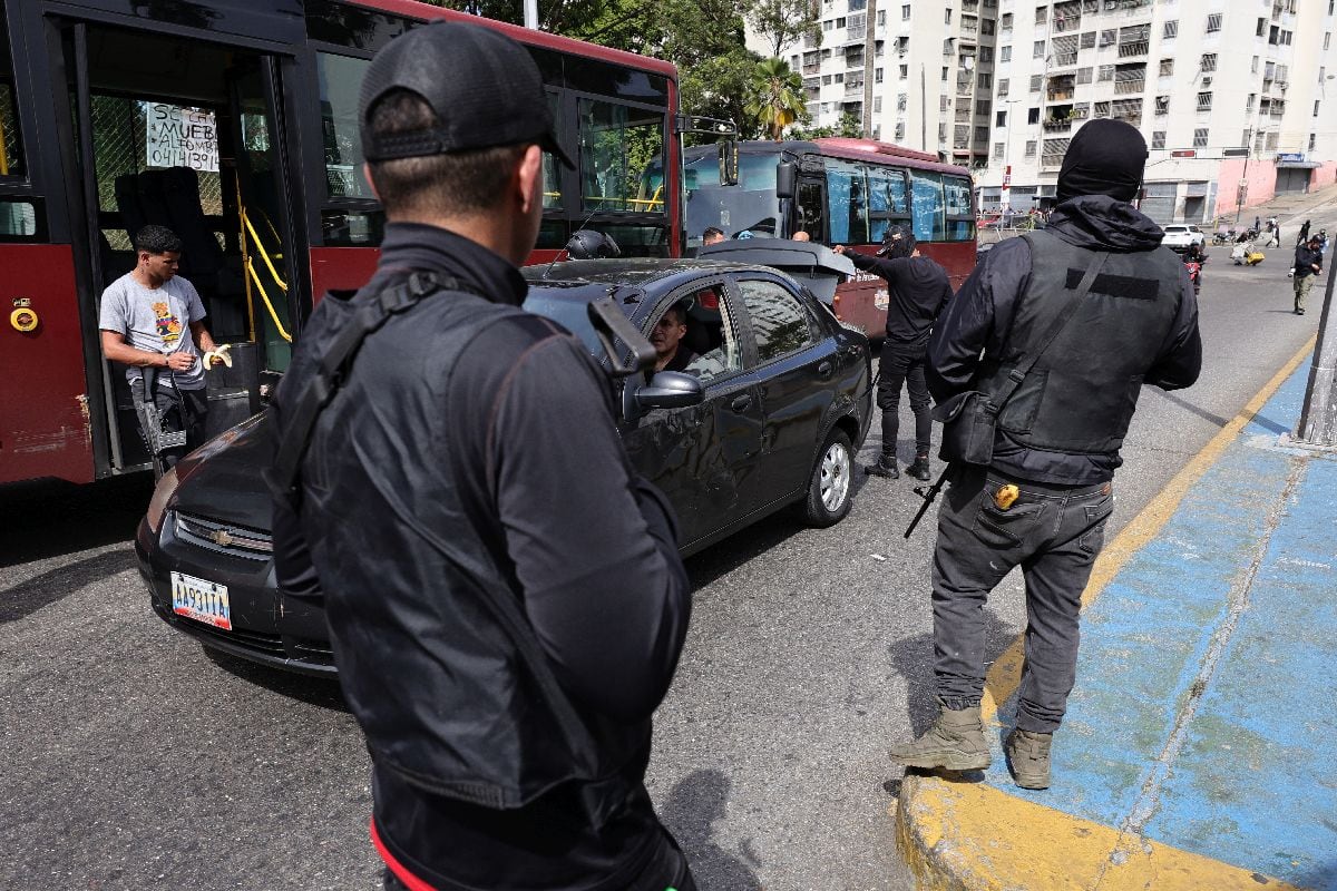 Hombres armados inspeccionan el baúl de un auto en Caracas, el 3 de enero.