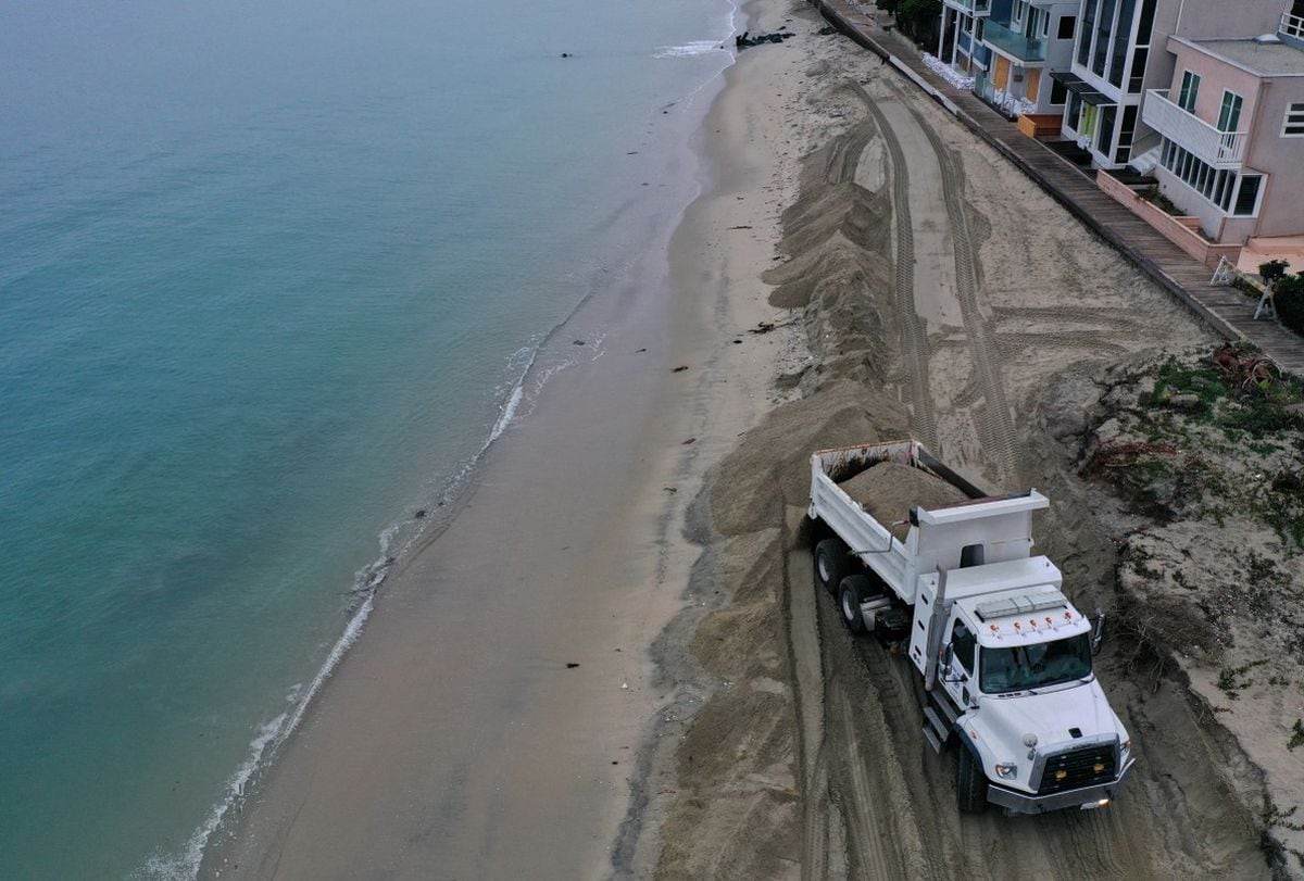 Un camión volquete descarga arena para construir barreras protectoras en la playa de Long Beach, California, el 25 de septiembre de 2026; estas medidas buscan proteger las viviendas ante el fuerte oleaje, las inundaciones costeras y la erosión de la playa provocados por la llegada del huracán Polo (Foto: Patrick T. Fallon / AFP)