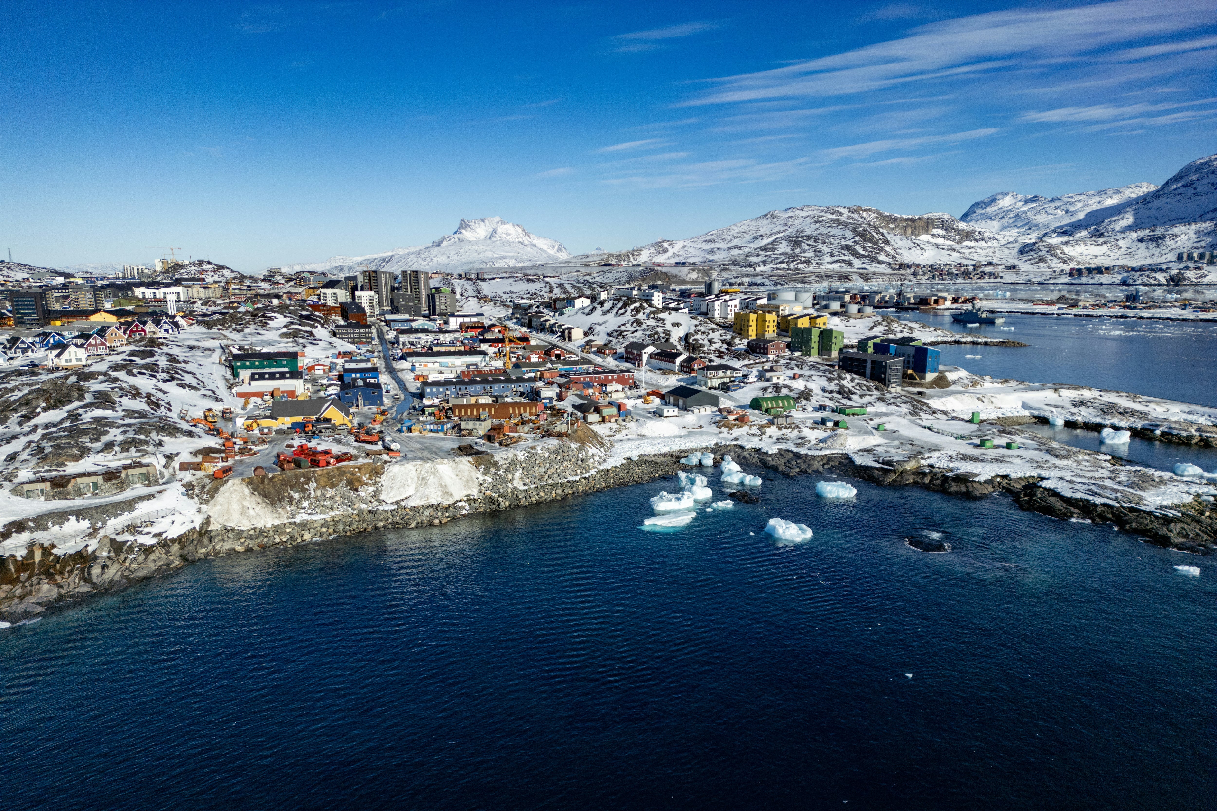 Esta vista aérea muestra icebergs flotando en las aguas bañadas por el sol, con edificios al fondo, frente a Nuuk, Groenlandia, el 11 de marzo de 2025. (Foto de Odd ANDERSEN / AFP).