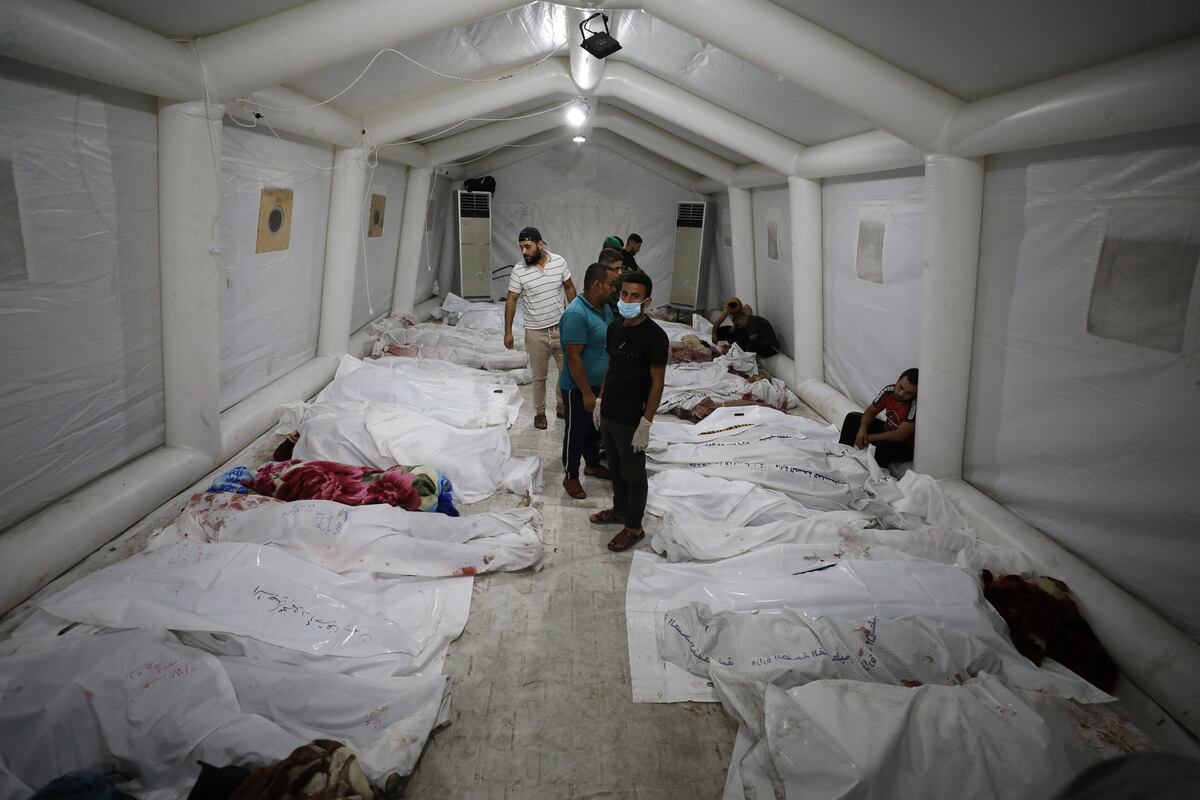 Personas junto a los cuerpos de palestinos muertos en ataques aéreos israelíes contra el hospital árabe Ahli en el centro de Gaza después de ser transportados al hospital Al-Shifa, el 17 de octubre de 2023. (Foto de Dawood NEMER / AFP)