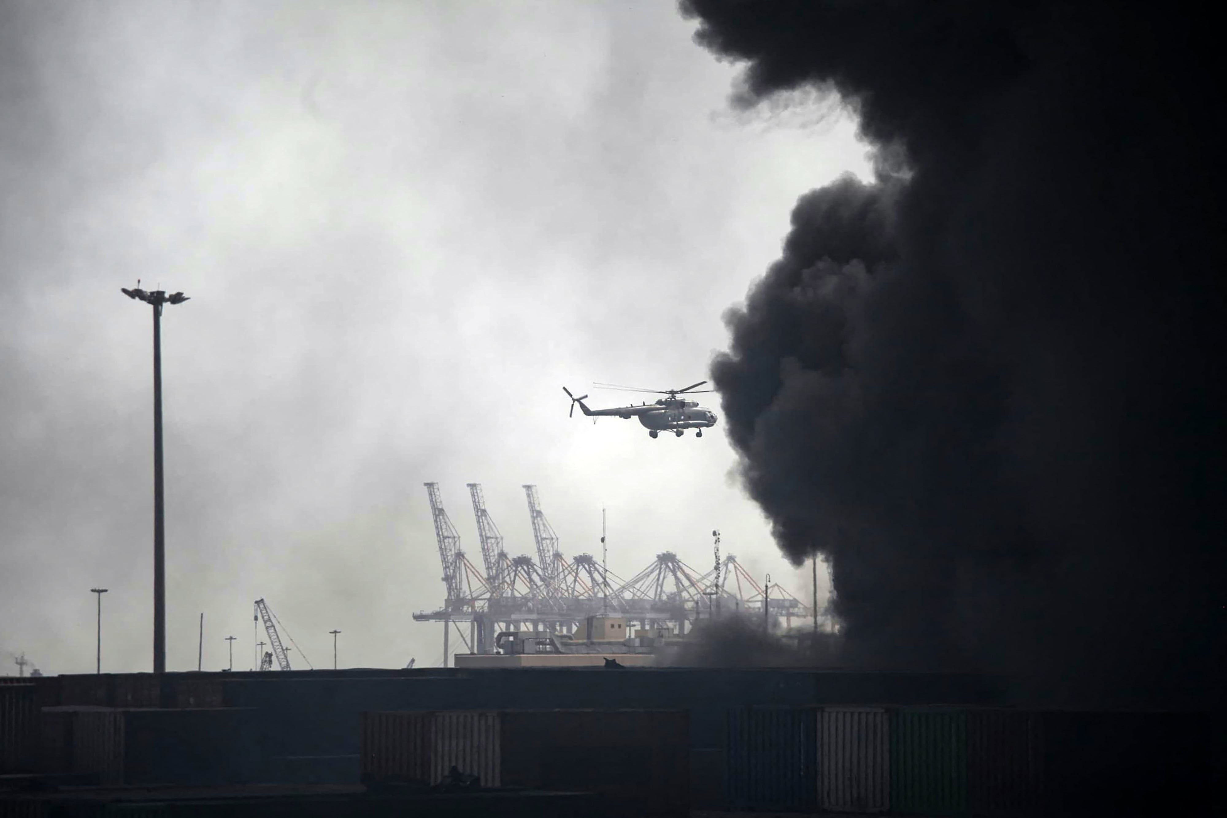 Un helicóptero sobrevuela el humo tras una explosión en el muelle del puerto de Shahid Rajaee, al suroeste de Bandar Abbas, en la provincia iraní de Hormozgán, el 26 de abril de 2025. (Foto de MOHAMMAD RASOLE MORADI / IRNA / AFP)