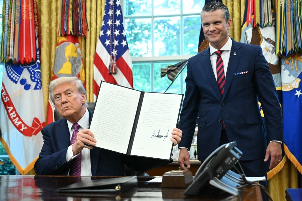 Donald Trump muestra una orden ejecutiva firmada mientras el secretario de Defensa, Pete Hegseth, observa desde la Oficina Oval de la Casa Blanca en Washington, D.C., el 5 de septiembre de 2025. El viernes, Trump firmó una orden que rebautiza el Departamento de Defensa como Departamento de Guerra, afirmando que enviaba un "mensaje de victoria" al mundo. Foto: AFP