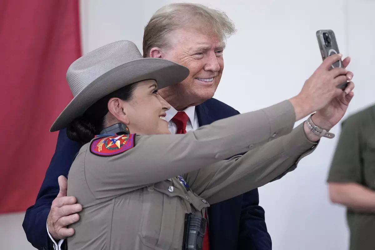 El candidato presidencial republicano y expresidente Donald Trump posa para una fotografía con un policía estatal de Texas mientras ayuda a servir comida a los soldados, policías y otras personas de la Guardia Nacional de Texas, el domingo 19 de noviembre de 2023, en Edimburgo, Texas. (Eric Gay / Associated Press)