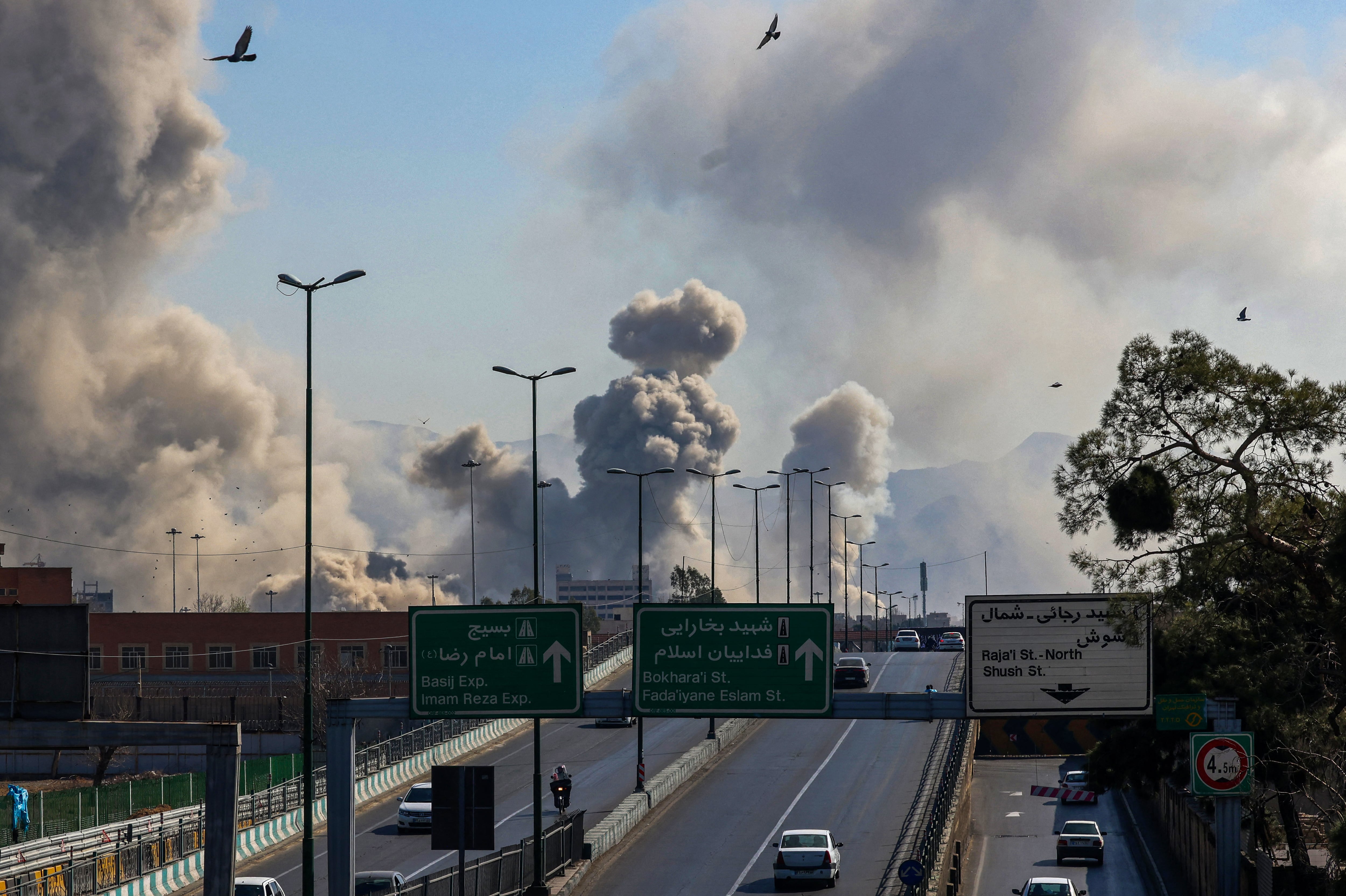 Automovilistas circulan por una autopista mientras columnas de humo se elevan tras un ataque en Teherán, Irán, el 5 de marzo de 2026. (Foto de ATTA KENARE / AFP).