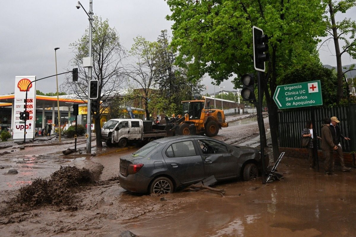 El aluvión en San Carlos de Apoquindo, en la comuna de Las Condes, arrastró vehículos particulares y un bus del transporte público RED tras las intensas lluvias registradas este jueves en Santiago de Chile. (Foto de RODRIGO ARANGUA / AFP)
