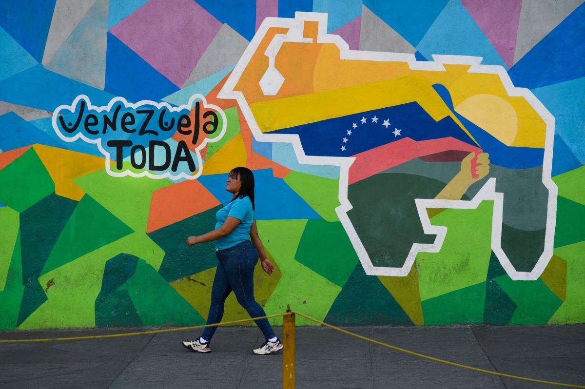 Una peatón pasa junto a un mural que dice "Toda Venezuela", durante un referéndum en Caracas, Venezuela, el domingo 3 de diciembre de 2023. El presidente Maduro está exacerbando la tensión regional al reavivar una disputa fronteriza latente durante mucho tiempo sobre el área conocida como el Esequibo. Fotógrafo: Gaby Oraá/Bloomberg