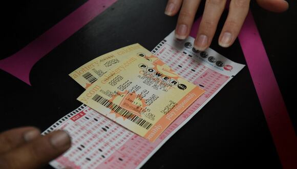 Una clienta recoge sus boletos de lotería Powerball de California en la famosa licorería Bluebird, considerada un minorista afortunado de boletos, en Hawthorne, California, el 13 de enero de 2016 (Foto: Mark Ralston / AFP)