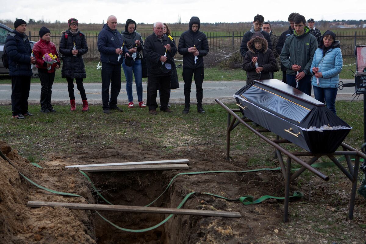 La gente se reúne junto a un ataúd con el cuerpo de Ruslan Nechyporenko, asesinado en medio de la invasión de Rusia, durante su funeral en la ciudad de Bucha. (REUTERS/Volodymyr Petrov)