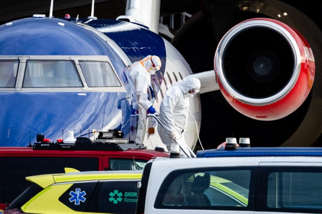 Esta fotografía muestra a dos personas con trajes de protección descendiendo de un avión medicalizado Bombardier Challenger 605 que supuestamente transportaba a algunos de los pasajeros del crucero MV Hondius, presuntamente infectado con hantavirus, en el aeropuerto de Schiphol, Ámsterdam, el 6 de mayo de 2026. (Foto de Jeffrey Groeneweg / ANP / AFP) / Países Bajos FUERA