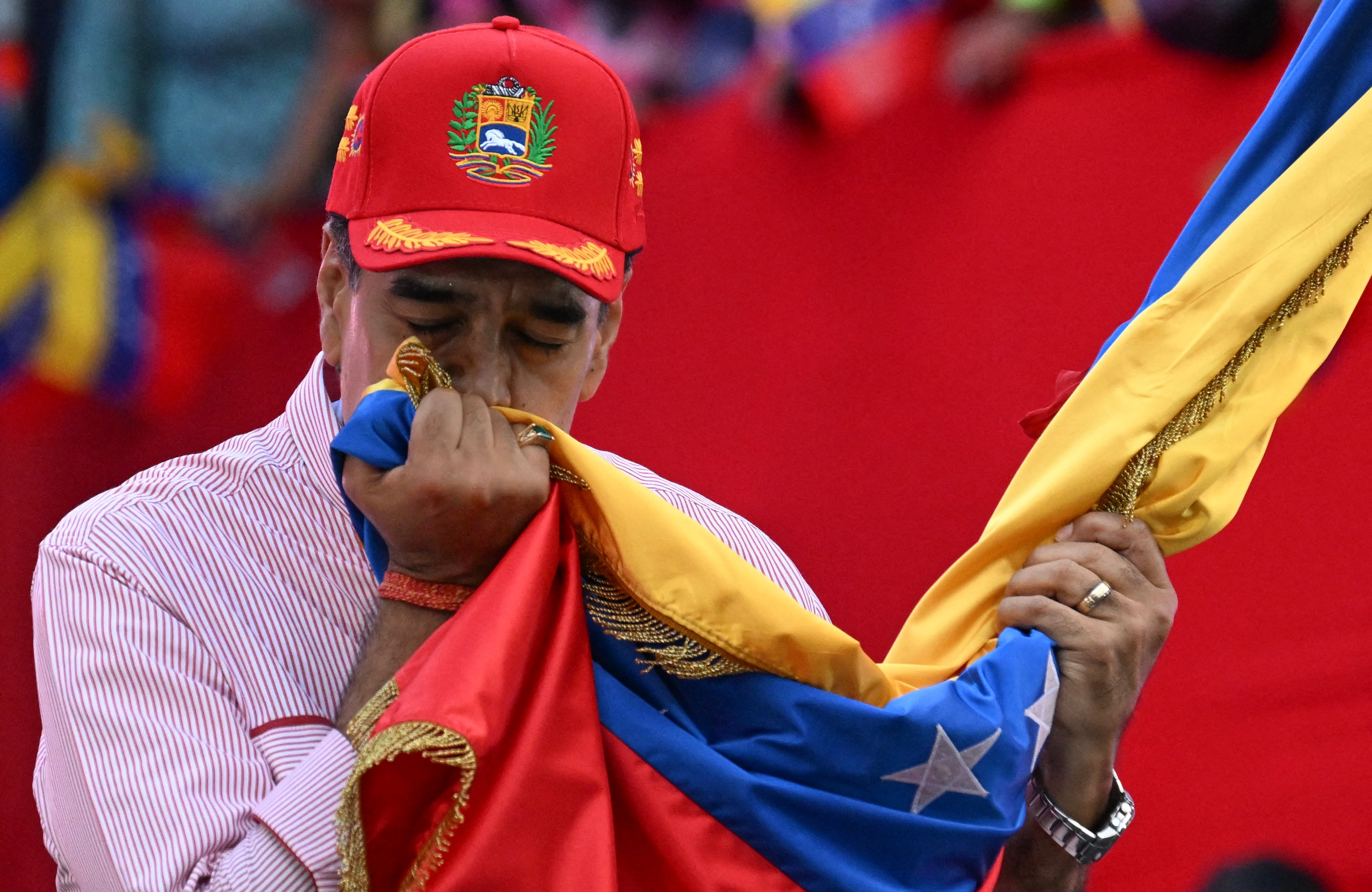 Nicolás Maduro besa la bandera nacional de Venezuela durante un mitin en Caracas el 1 de diciembre de 2025. (Foto de Juan BARRETO / AFP).