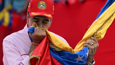Nicolás Maduro besa la bandera nacional de Venezuela durante un mitin en Caracas el 1 de diciembre de 2025. (Foto de Juan BARRETO / AFP).
