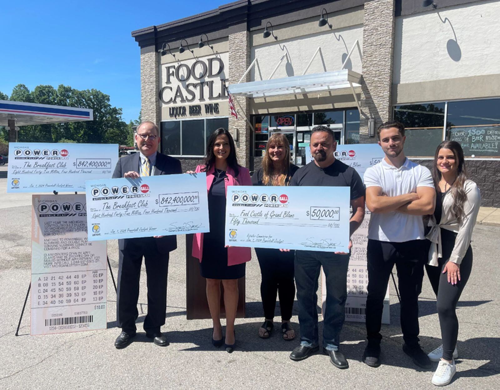 La comisionada de lotería, Suzanna Shkreli, presenta al representante del club de lotería The Breakfast Club, Mark K. Harder, con el cheque de US$842,4 millones y a la familia Nannoshi, de la tienda Food Castle de Grand Blanc, con su cheque US$50,000 por la venta del boleto (Foto: Lotería de Michigan)