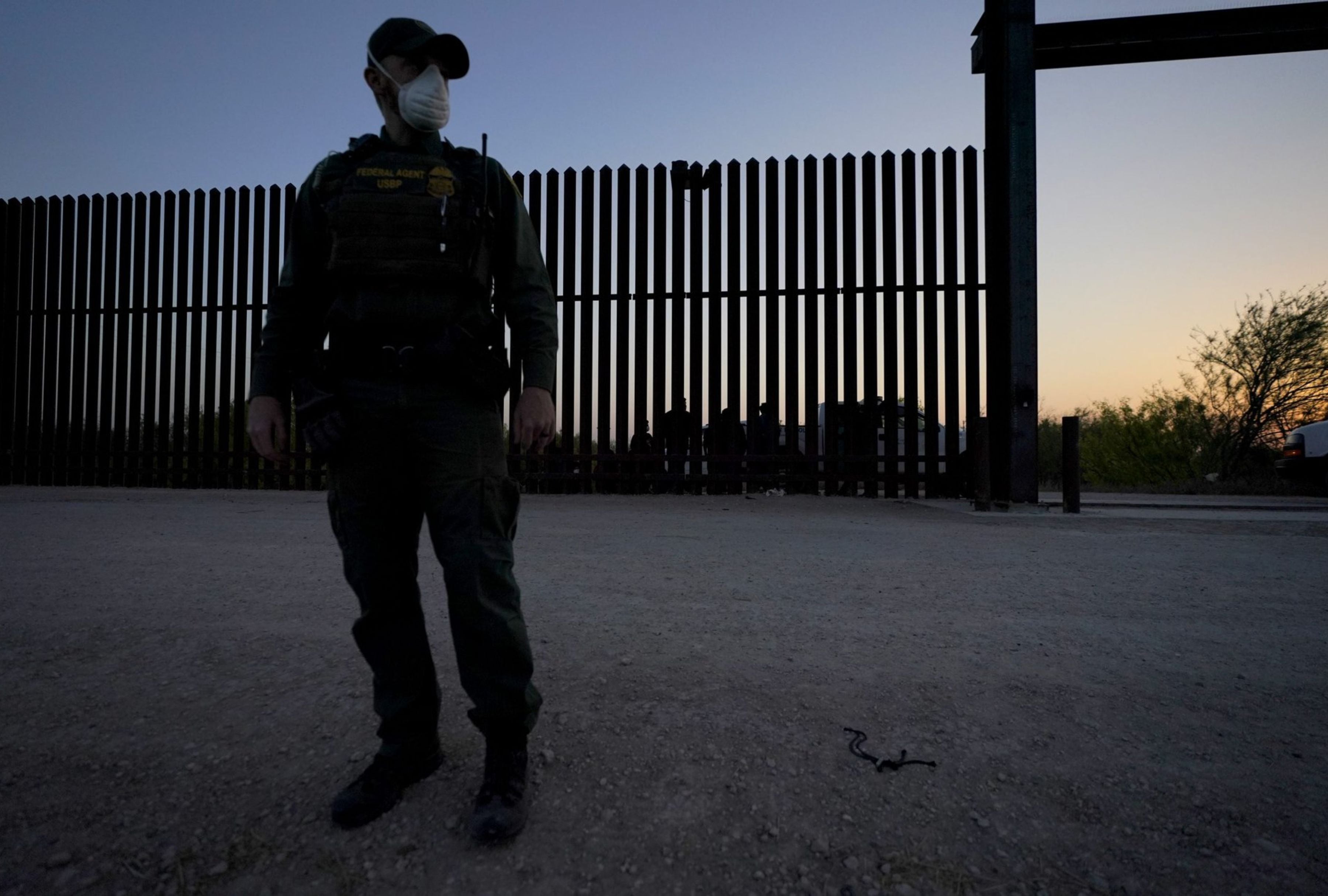 Un agente de Aduanas y Protección Fronteriza de Estados Unidos está destacado en el muro fronterizo entre EE. UU. y México en Abram-Perezville, Texas, mientras los agentes detienen a migrantes en marzo de 2021. | Crédito: Julio Cortez / AP