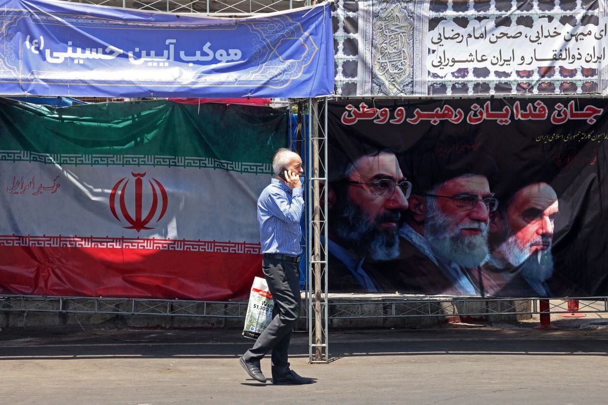 Un hombre pasa junto a la bandera nacional de Irán en la plaza Vanak de Teherán el 10 de junio de 2026. Foto: ATTA KENARE / AFP