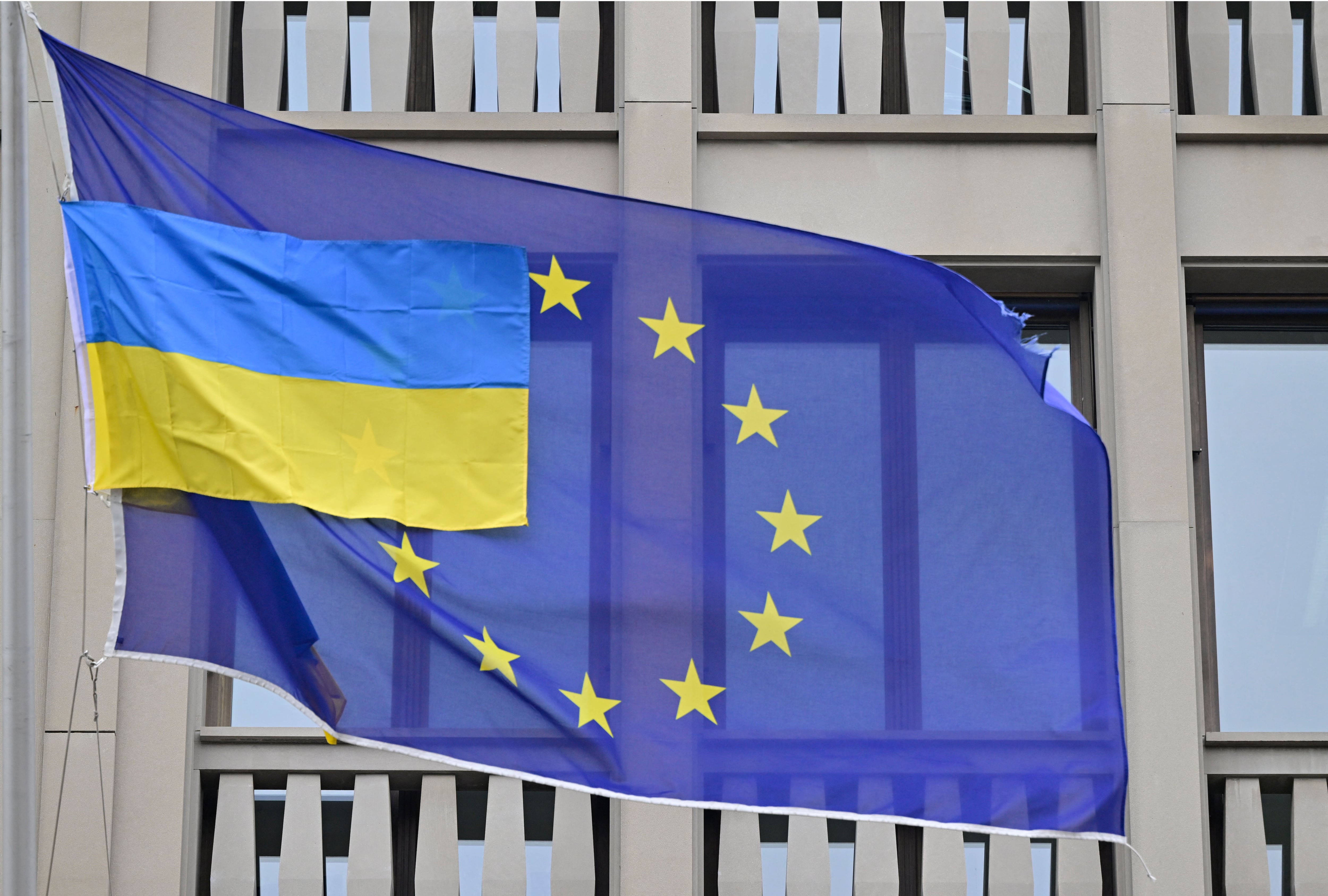 A smaller Ukrainian flag flies next to a flag of the European Union in front of the EU-representation office in Berlin on April 5, 2022. (Photo by John MACDOUGALL / AFP)