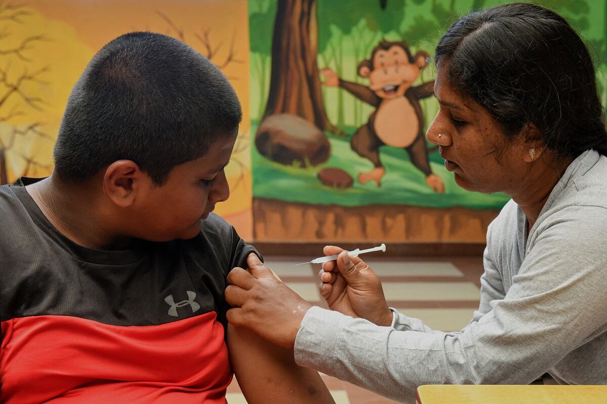 Un trabajador de la salud inocula a un estudiante de escuela con una dosis de la vacuna 'Corbevax' durante una campaña de vacunación para niños en el grupo de edad de 12 a 14 años, en Bangalore el 9 de mayo de 2022. (Foto de Manjunath Kiran / AFP)