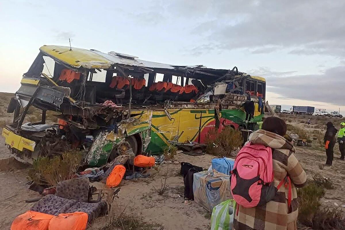 Una mujer camina cerca de los restos de un autobús que chocó con otro en una carretera cerca de Uyuni, Bolivia. (Foto de la Policía boliviana / AFP)