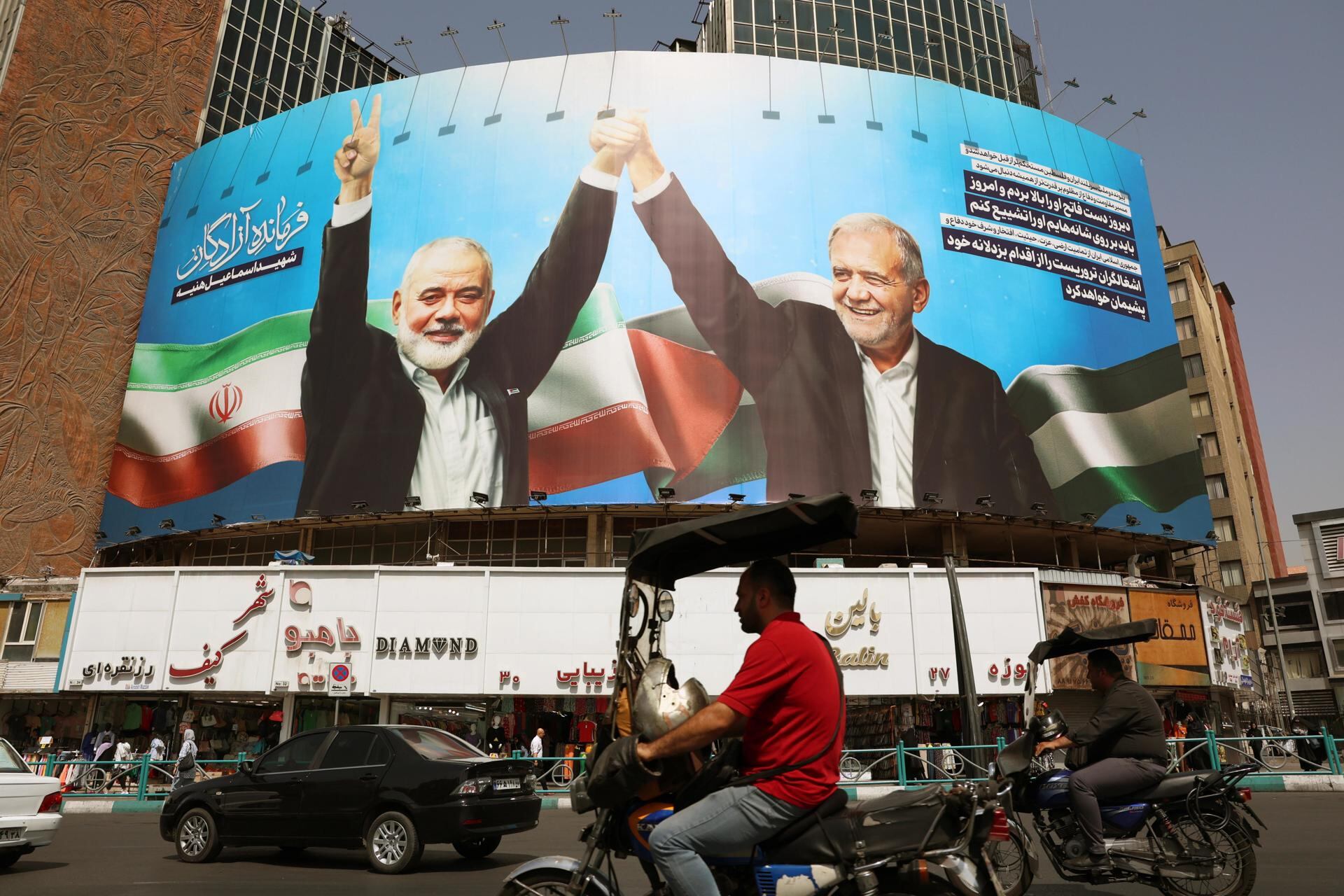 Un cartel donde se ve al presidente de Irán Masoud Pezeshkian (der) y al difunto líder de Hamas, Ismail Haniyeh, en la plaza Valiasr en Teherán, el 5 de agosto de 2024. (EFE/EPA/ABEDIN TAHERKENAREH).