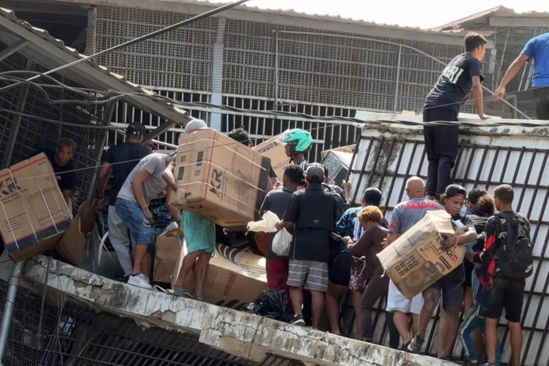 Personas haciendo saqueos en un establecimiento comercial en la localidad de Catia La Mar, en el estado costero de La Guaira, Venezuela. (EFE/ Rayner Peña R).