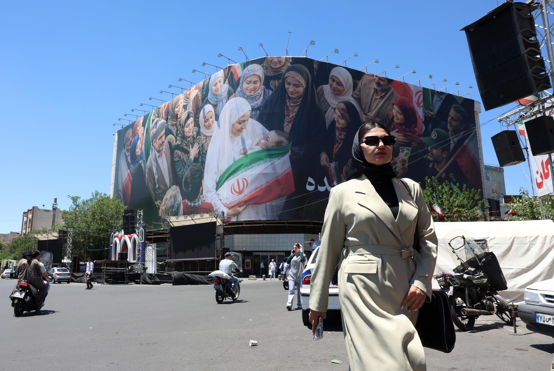 Una mujer camina junto a una enorme valla publicitaria en una calle de Teherán, Irán, el lunes 25 de mayo de 2026. (EFE/ Abedin Taherkenareh).