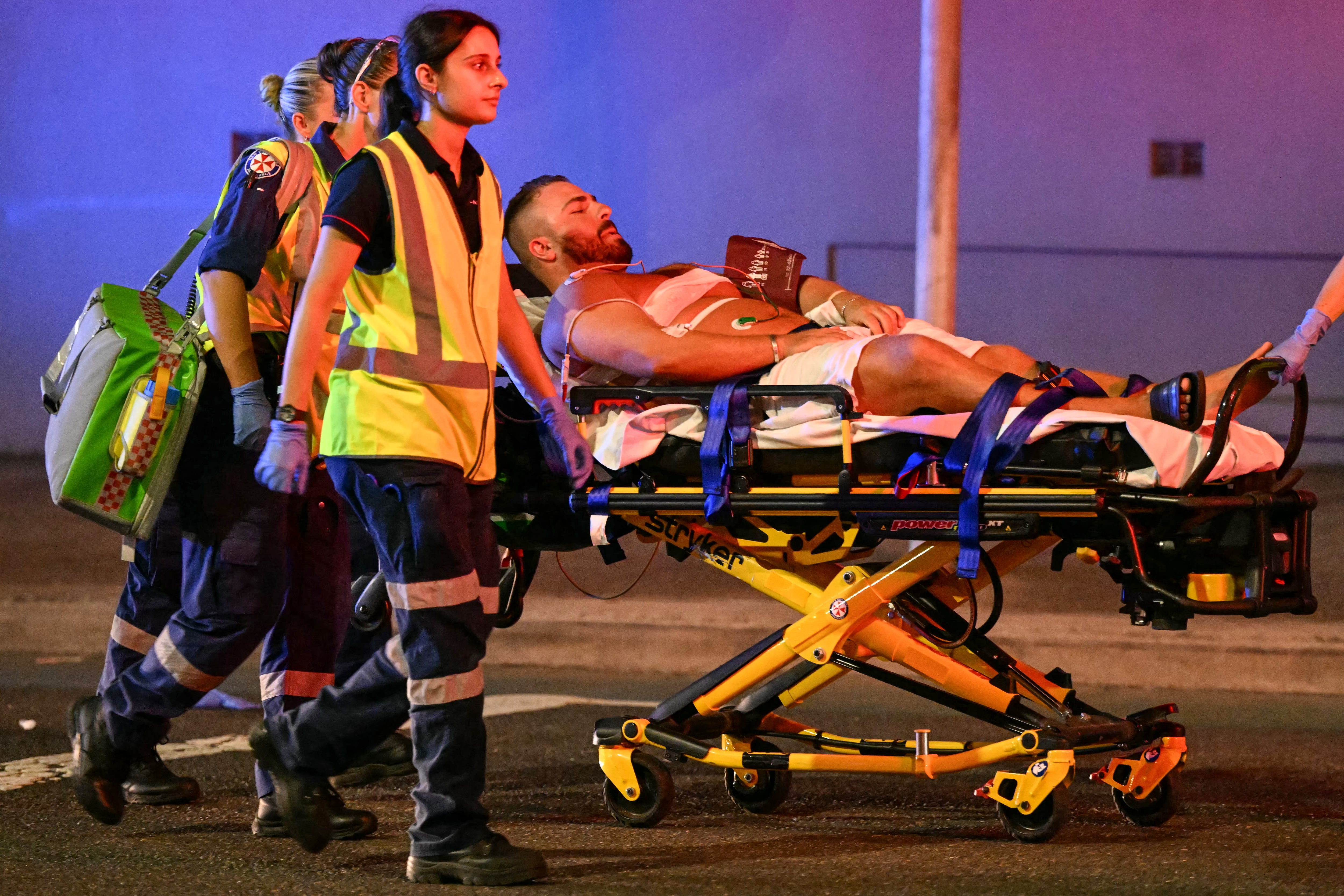 Personal sanitario traslada a un hombre en camilla a una ambulancia tras un tiroteo en Bondi Beach, Sídney, Australia, el 14 de diciembre de 2025. (Foto de Saeed KHAN / AFP).