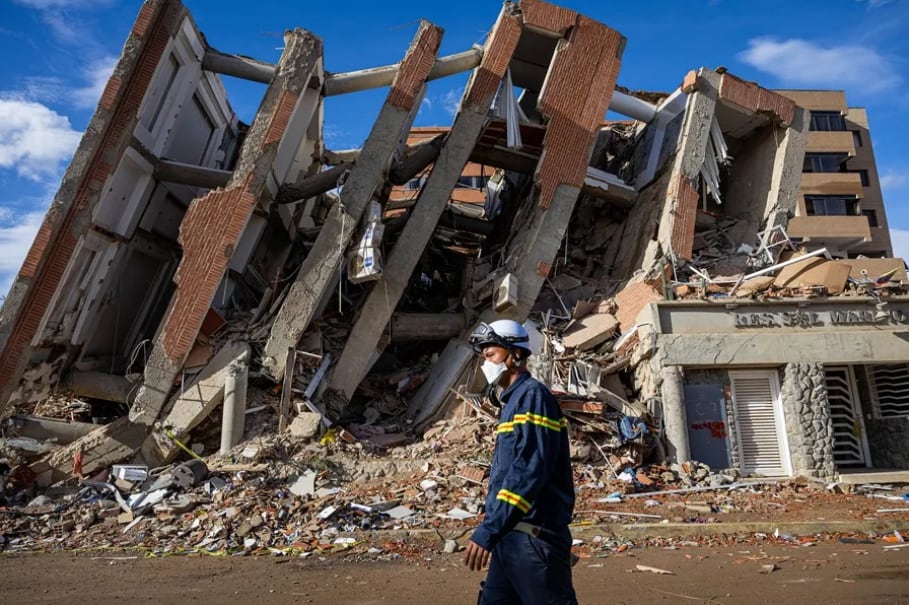 Un rescatista de Vietnam camina frente a escombros de edificaciones destruidas en Catia La Mar, La Guaira (Venezuela). Foto: EFE.