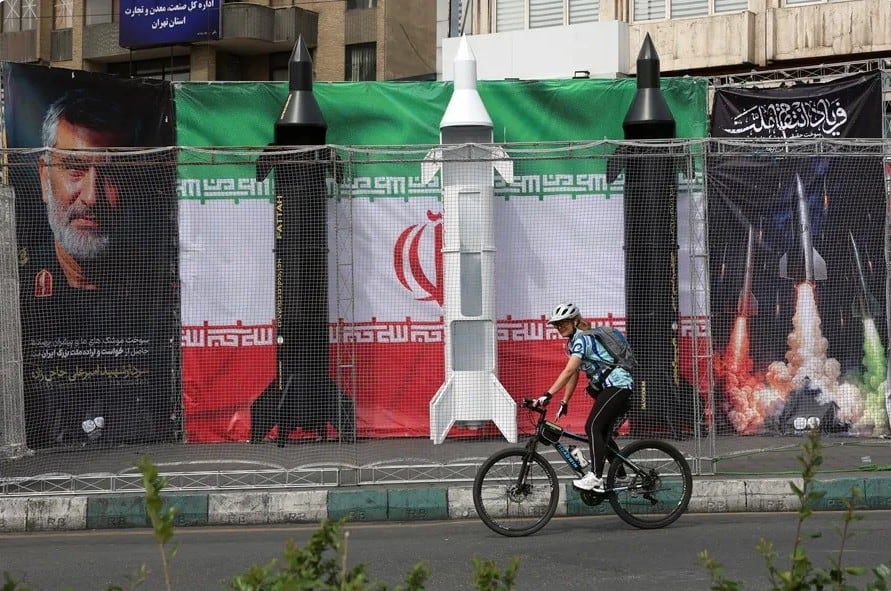 Fotografía de archivo de una persona manejando una bicicleta frente a una bandera de Irán. EFE/ Abedin Taherkenareh