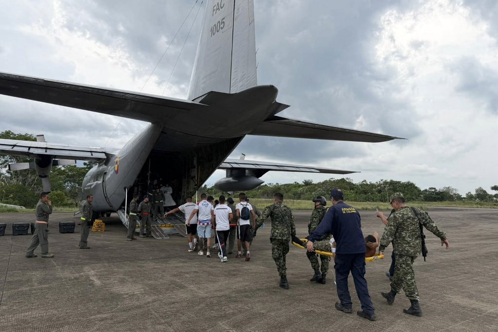 Una fotografía distribuida por las Fuerzas Armadas colombianas muestra a miembros de la Fuerza Aeroespacial Colombiana trasladando a personas heridas en camillas para ser embarcadas en un avión en Puerto Leguizamo, Colombia, cerca de la frontera sur con Ecuador, el 23 de marzo de 2026. Un avión militar colombiano con 125 soldados y tripulantes a bordo se estrelló durante el despegue el 23 de marzo de 2026, y se teme que hasta 80 personas hayan fallecido. El avión Hércules se precipitó a tierra poco después de despegar de Puerto Leguizamo, cerca de la frontera sur con Ecuador, dejando restos en llamas esparcidos por la selva. (Foto de Handout / Fuerzas Armadas Colombianas / AFP)