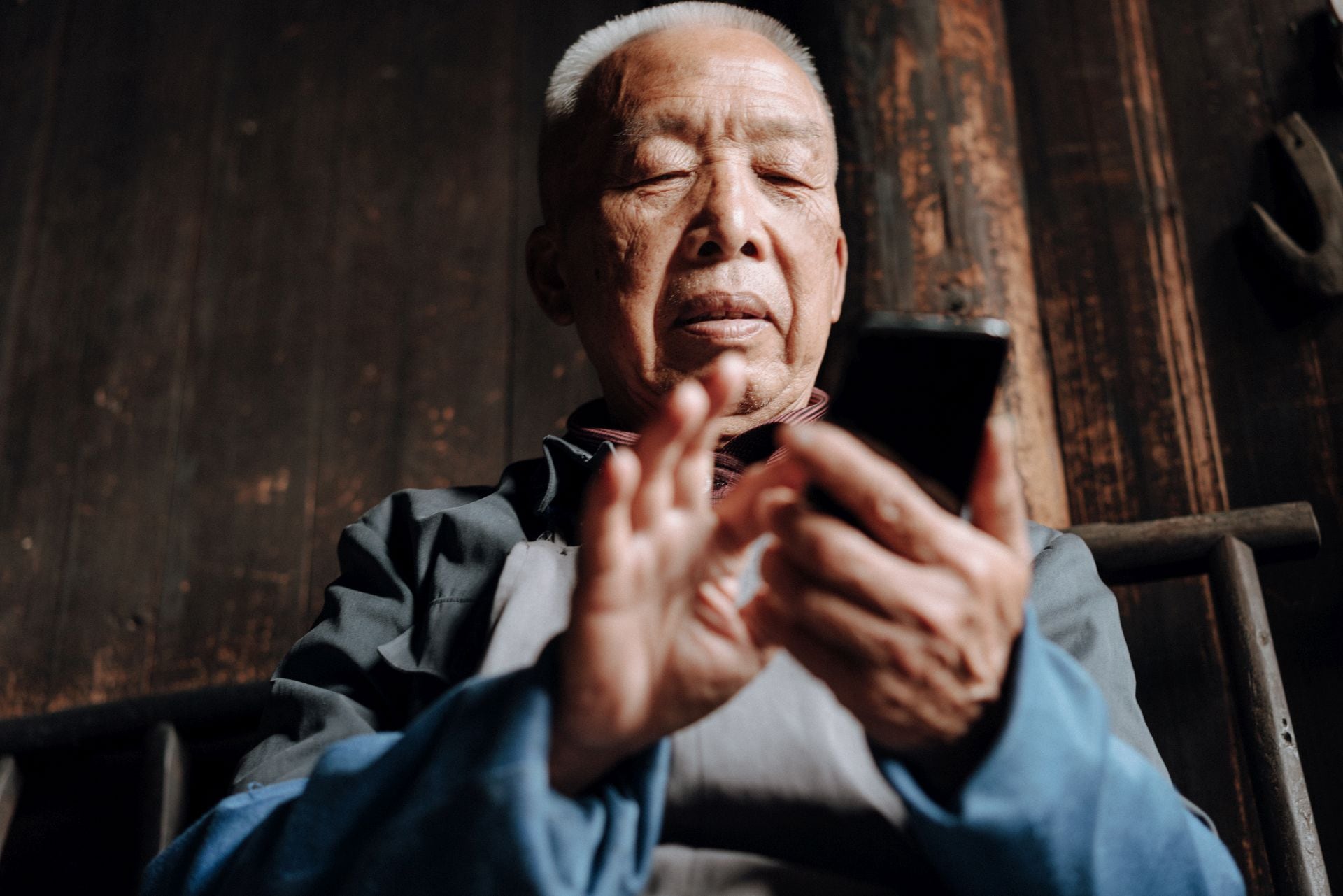 Imagen referencial de hombre mayor chino usando un teléfono móvil. (iStock)