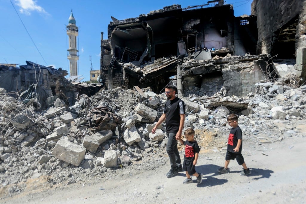 Un hombre camina con sus hijos junto a un edificio destruido tras regresar a la aldea de Nabatieh, en el sur del Líbano, el 18 de junio de 2026. El ejército israelí declaró el 18 de junio que continuará operando en el sur del Líbano y "eliminará las amenazas" más allá de su denominada zona de seguridad, después de que Estados Unidos e Irán firmaran un acuerdo para poner fin a la guerra en Oriente Medio, incluyendo el Líbano. (Foto de MAHMOUD ZAYYAT / AFP)
