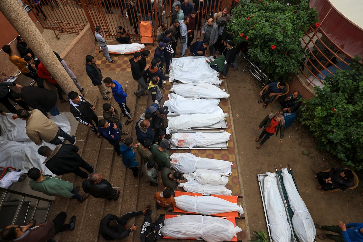 Los palestinos lamentan la muerte de sus seres queridos tras el bombardeo israelí en el sur de la Franja de Gaza el 5 de diciembre de 2023, mientras varios cuerpos yacen afuera de un hospital en Khan Yunis, en medio de continuas batallas entre Israel y el grupo militante Hamas. (Foto de Mahmud HAMS / AFP)