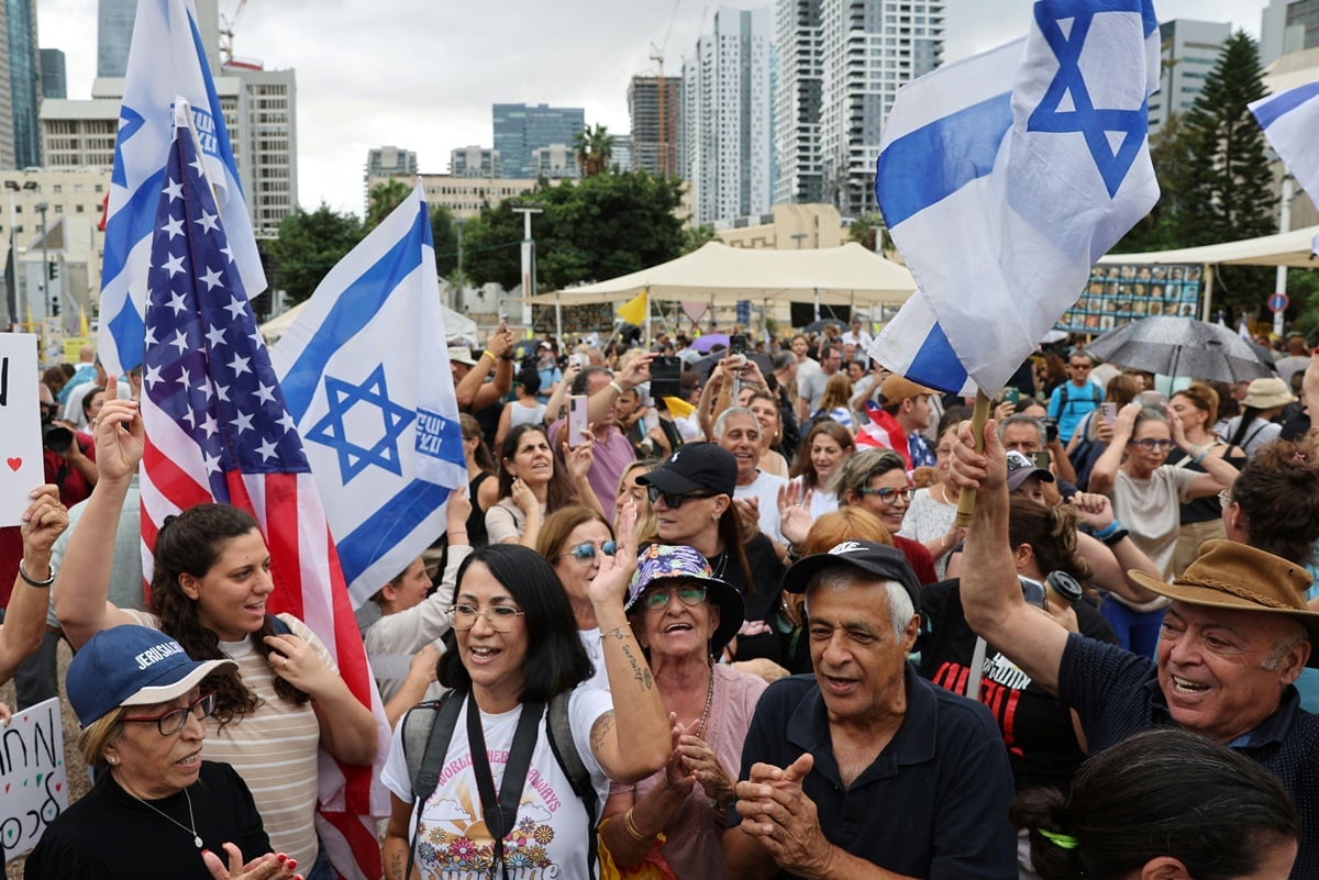 La gente ondea banderas estadounidenses e israelíes en la Plaza de los Rehenes en Tel Aviv el 9 de octubre de 2025, tras el anuncio de un nuevo acuerdo de alto el fuego en Gaza. (Foto: AFP)