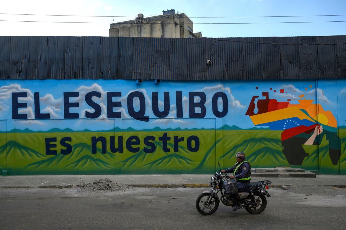 Un miembro de la Policía Nacional Bolivariana (PNG) pasa junto a un mural que dice "El Esequibo es nuestro", durante un referéndum en Caracas, Venezuela, el domingo 3 de diciembre.