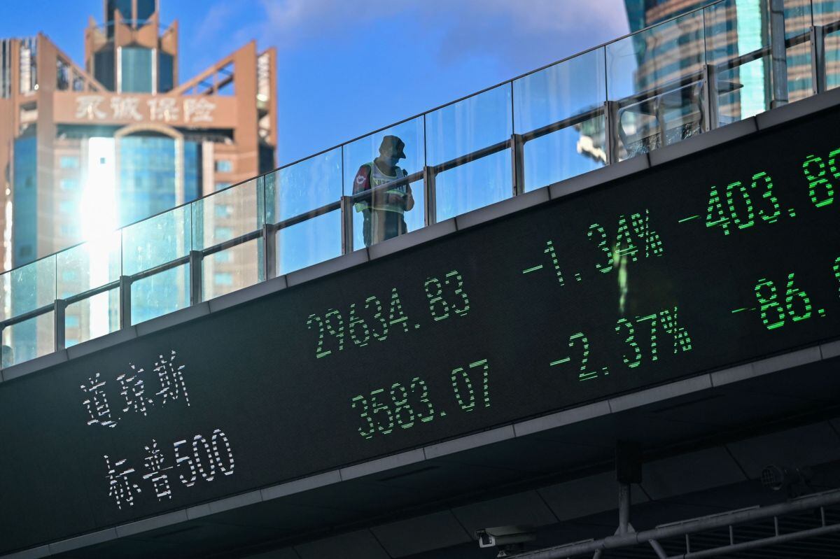 Un guardia cruza un puente con un tablero indicador de acciones en el distrito financiero de Lujiazui en Shanghai Fotógrafo: Hector Retamal/AFP/Getty Images