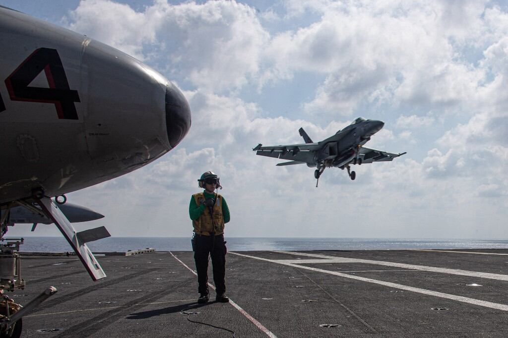 Esta fotografía, cortesía de la Armada de los EE. UU. y publicada el 15 de octubre de 2023, muestra al contramaestre de primera clase (equipo) Wesley Moore, de Tampa, Florida, observando un F/A-18E Super Hornet, asignado a los "Tomcatters" del Escuadrón de Cazas de Ataque (VFA) 31, aterrizar en la cubierta de vuelo del portaaviones más grande del mundo, el USS Gerald R. Ford (CVN 78), en el Mediterráneo Oriental, el 13 de octubre de 2023. (Foto de Jacob Mattingly / US NAVY / AFP)