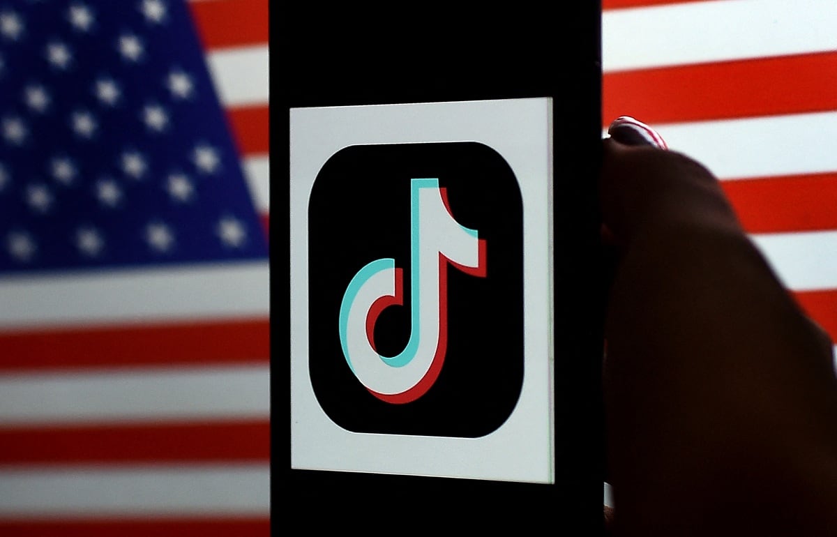 El logotipo de la aplicación de redes sociales, TikTok, se muestra en la pantalla de un teléfono sobre un fondo de bandera de Estados Unidos, el 3 de agosto de 2020. (Olivier DOULIERY / AFP)