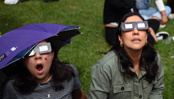 Unas mujeres viendo un eclipse solar con la protección requerida en la vista (Foto: AFP)