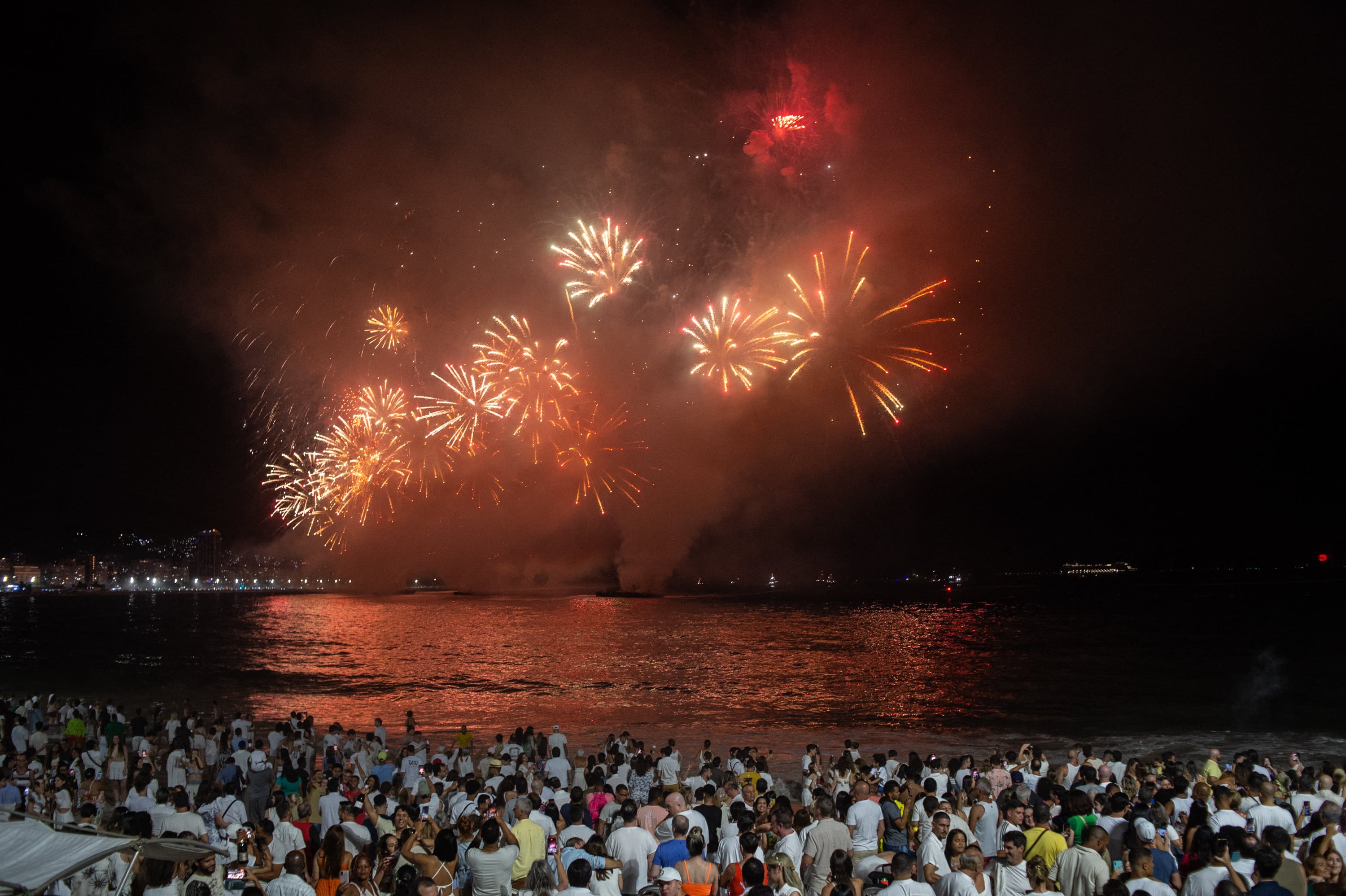 La gente observa los tradicionales fuegos artificiales de Año Nuevo en la playa de Copacabana, en Río de Janeiro, Brasil, el 1 de enero de 2024. (Foto de TERCIO TEIXEIRA / AFP).