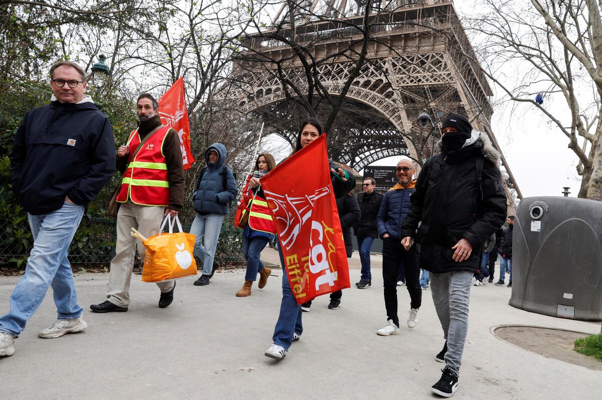 Los manifestantes sostienen banderas de los sindicatos CGT durante una huelga del personal de la Torre Eiffel. (Foto: AFP)