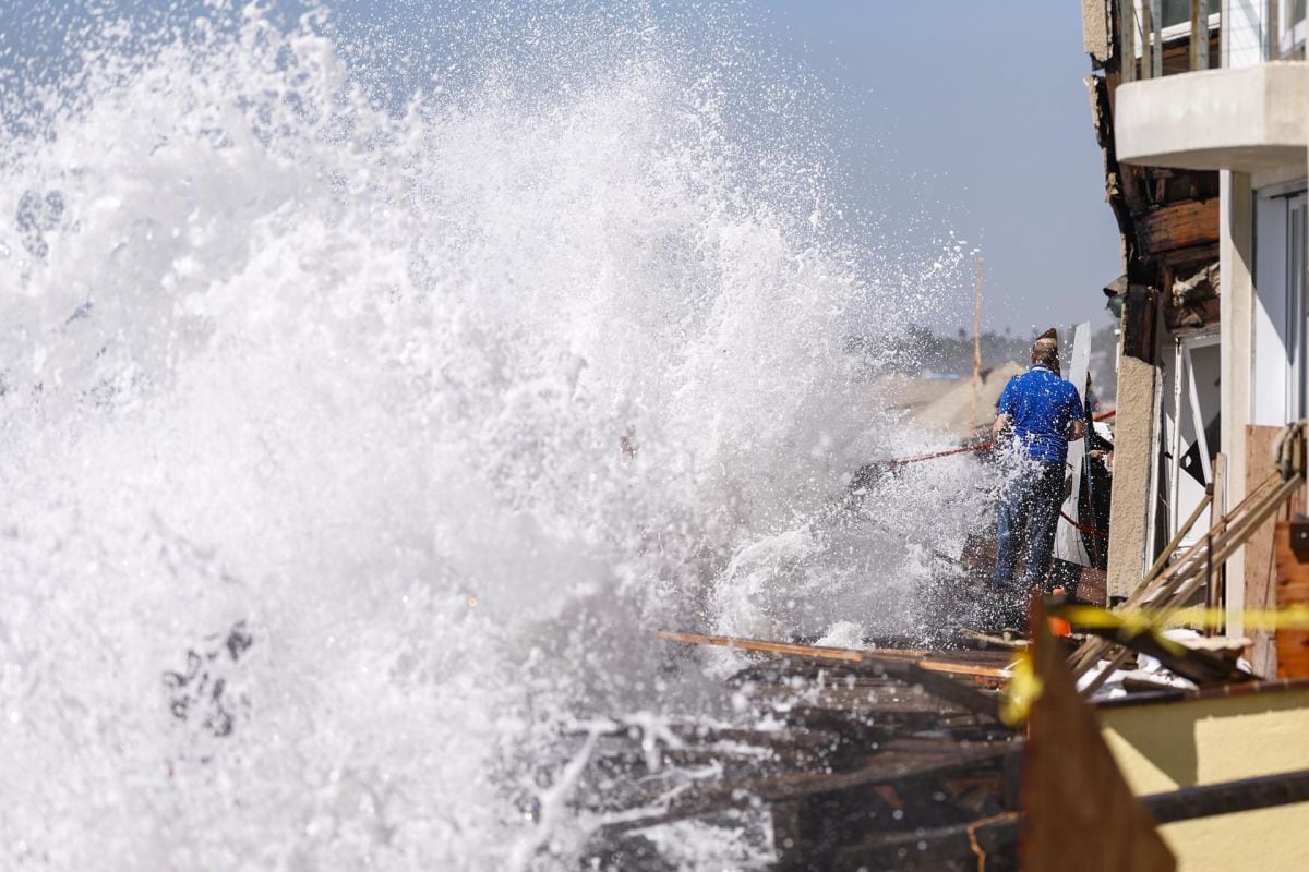 Unos residentes permanecen en el muelle después de que el oleaje rompiera a lo largo de la Península en Long Beach, California, el 9 de octubre de 2026, mientras un fuerte oleaje asociado a la tormenta tropical Rachel se combina con las mareas altas, provocando inundaciones costeras y daños en propiedades frente al mar (Foto: EFE/EPA/Chris Torres)
