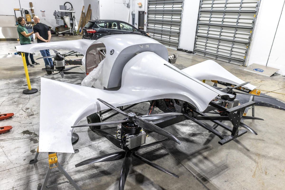 El fundador y director ejecutivo de Doroni Aerospace, Doron Merdinger (d), habla con un visitante frente al prototipo de su avión eléctrico de despegue y aterrizaje vertical (eVOLT). EFE/EPA/CRISTÓBAL HERRERA-ULASHKEVICH