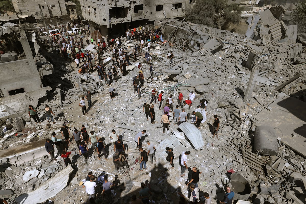 Una visión general de los edificios destruidos mientras la gente se reúne para buscar víctimas tras un ataque aéreo israelí en Rafah, en el sur de la Franja de Gaza, el 17 de octubre de 2023. (Foto de MOHAMMED ABED / AFP)