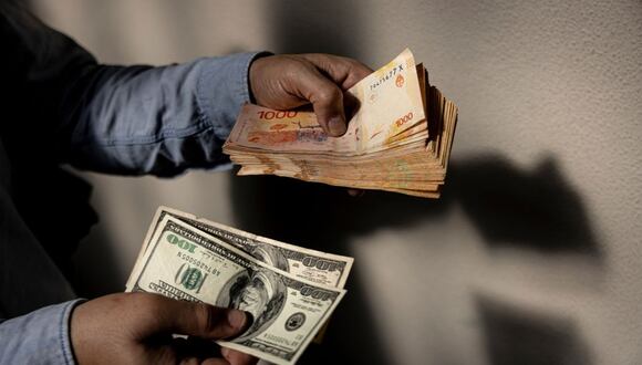 Un cambista tiene billetes de cien dólares estadounidenses y billetes de 1000 pesos en Buenos Aires, Argentina, el jueves 27 de abril de 2023.