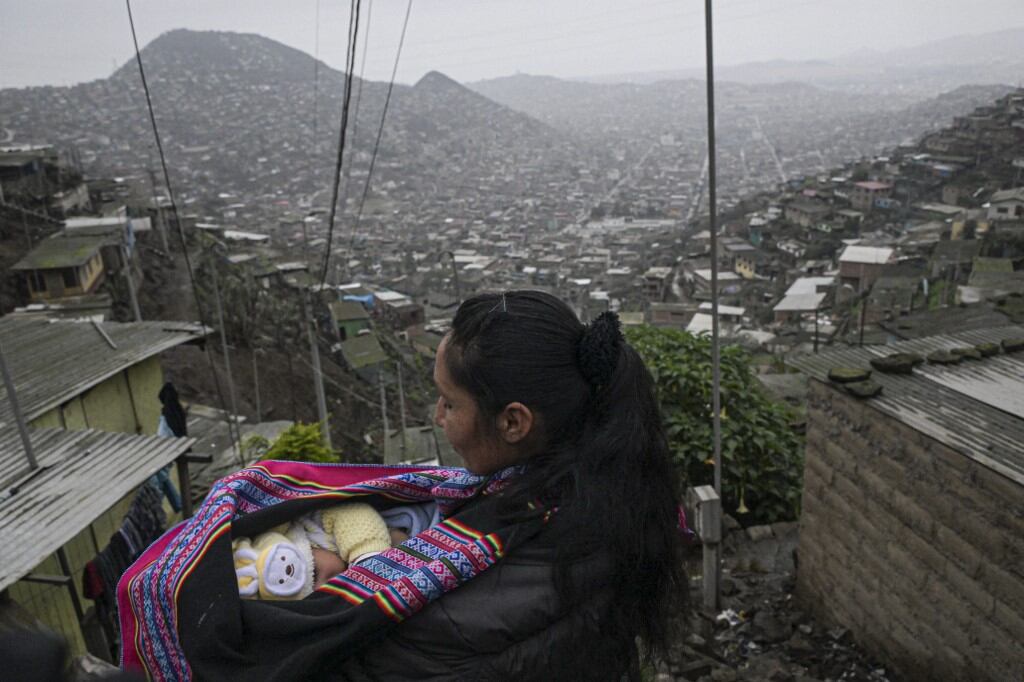 Rosa Huachaca (39) llega con su hijo Mateo, de 3 meses, a cocinar a un comedor comunitario en el distrito de Villa María del Triunfo, en las afueras del sur de Lima, el 21 de septiembre de 2023. (Foto de ERNESTO BENAVIDES/AFP)