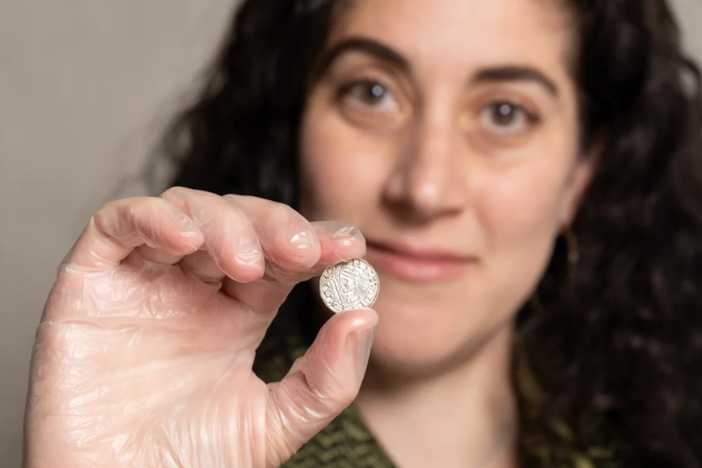 Una mujer del Museo Británico sosteniendo una de las monedas que fueron encontradas y que, en conjunto, valen más más de US$5 millones (Foto: Museo Británico)