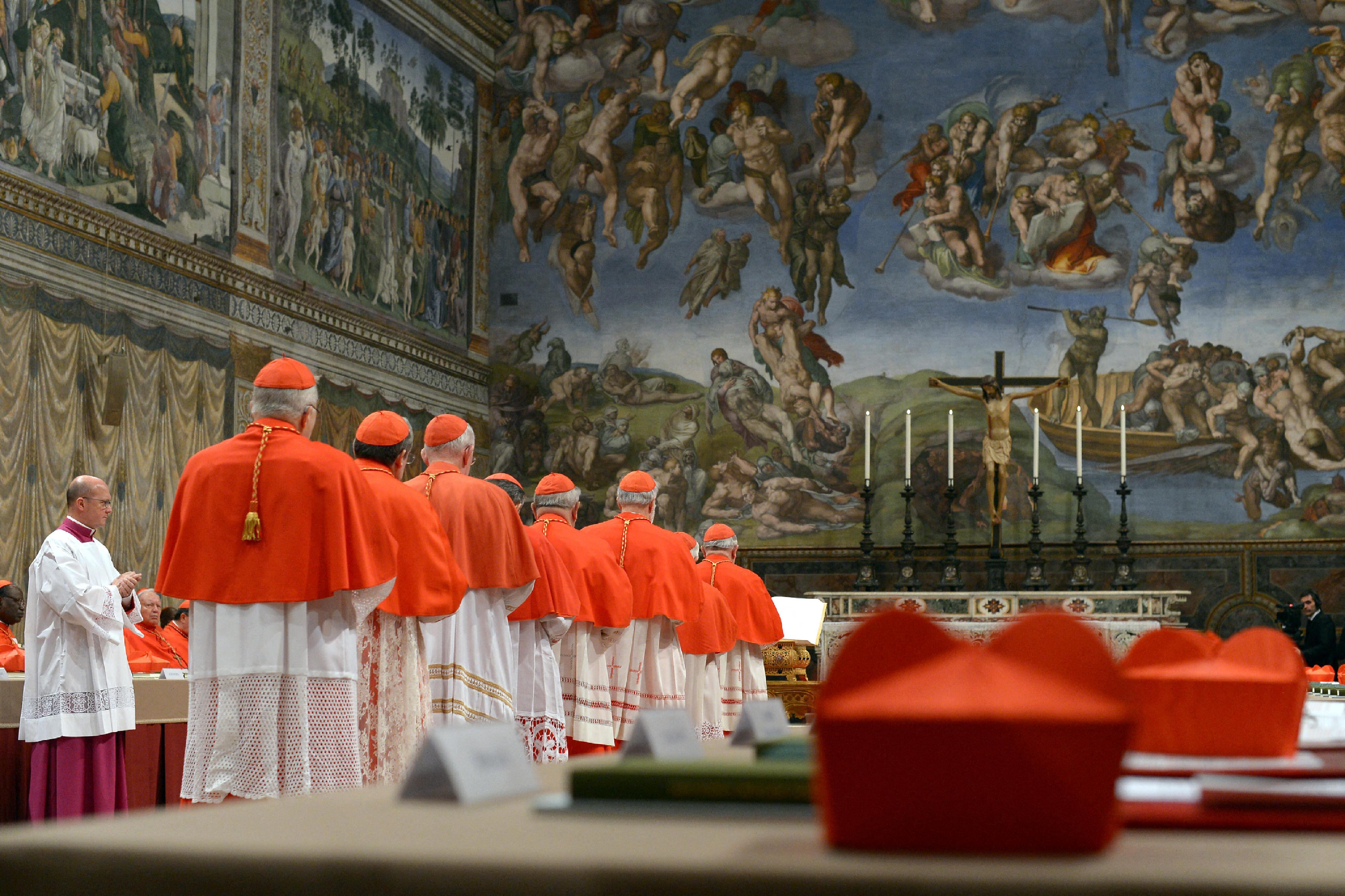 Esta imagen, difundida por la Oficina de Prensa, muestra a los cardenales haciendo fila en la Capilla Sixtina para jurar sobre la Biblia que jamás revelarán los secretos de sus deliberaciones antes del inicio del cónclave en el Vaticano el 12 de marzo de 2013. (Foto de OSSERVATORE ROMANO / AFP)